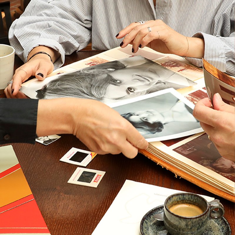 Triage de photographies anciennes étalées sur une table en bois lors d'une séance de sélection.